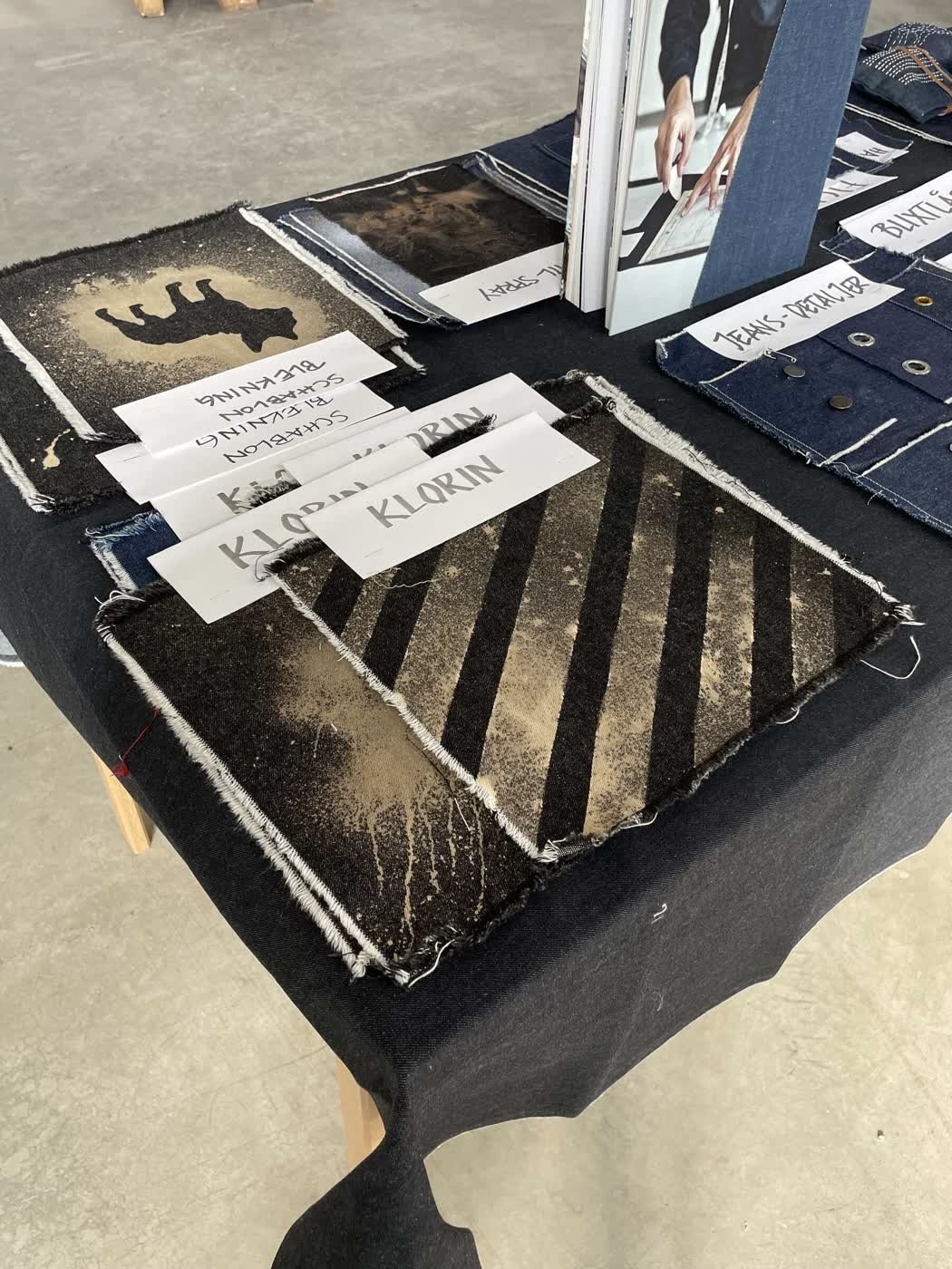 A denim sample board of bleaching and stencil techniques with handwritten Swedish labels.