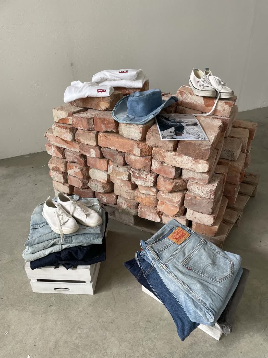 A styled denim display on reclaimed bricks with white Levi's sneakers and folded Levi's jeans.